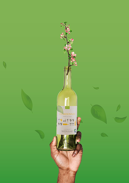 GH-Nachhaltigkeit am Beispiel Bio-Mehrweg-Weine (1) Hand hält Flasche WEIN:BAR – dem Bio-Mehrweg-Wein von GH