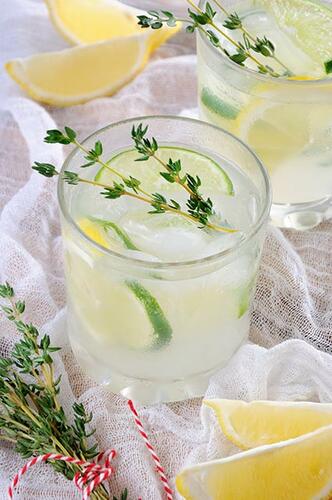 Cocktail Limoncello-Gin serviert mit Limette und Thymian