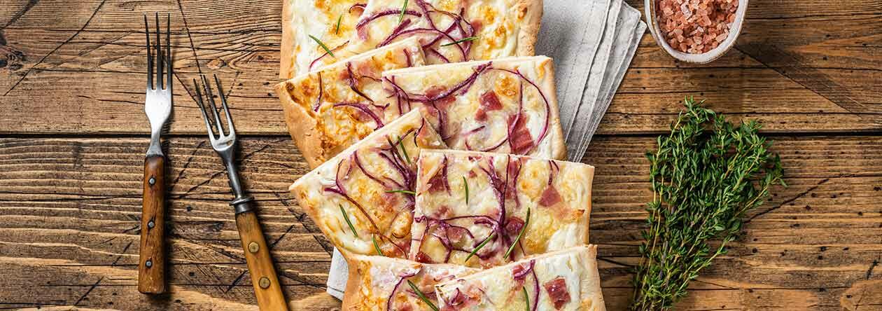 Knuspriger Flammkuchen mit Zwiebeln, Speck und Kräutern – perfekt zu Federweißer